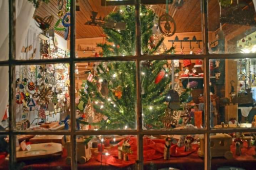 exterior of a store window decorated with a treet and ornaments during the christmas season in dillsboro nc